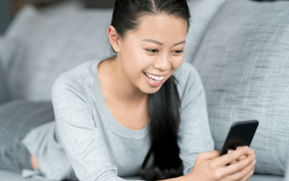 Filipino Woman at Home Using a Dating App on Her Cellphone