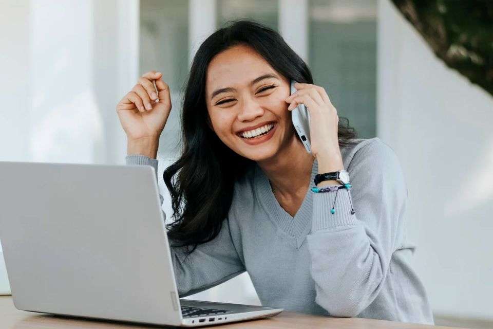 Filipina Woman Smiling While on a Phone Call - How to Court a Filipina Long Distance - Blossoms Dating Blog
