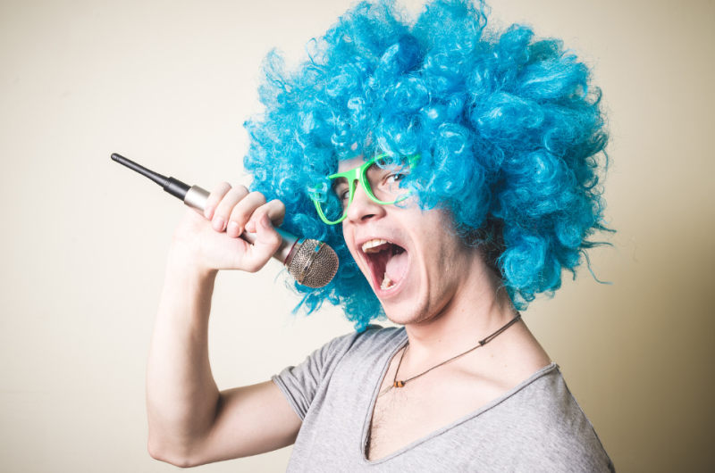 Funny Man Wearing a Blue Wig While Holding a Microphone