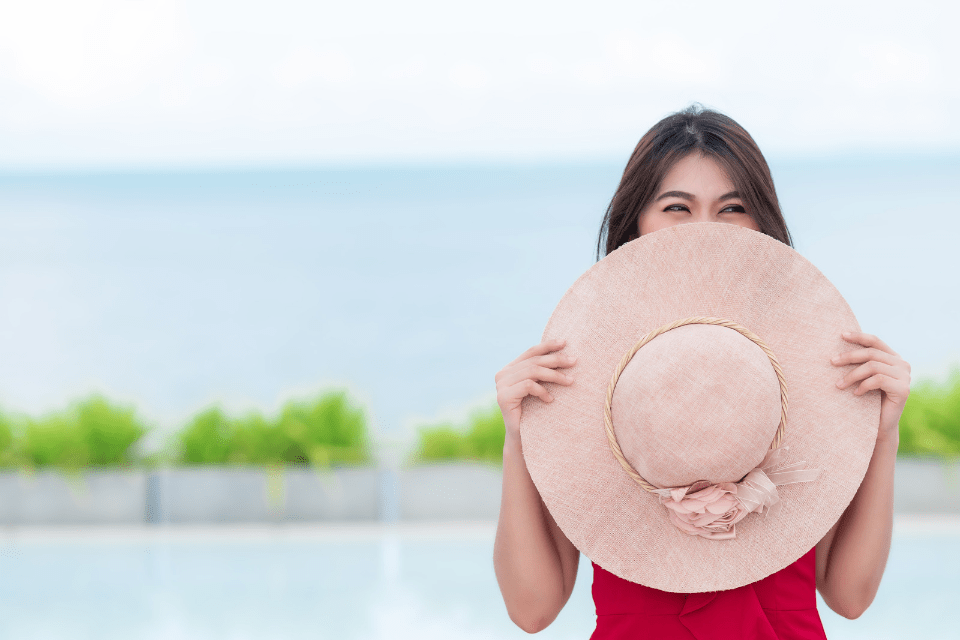 Smiling Filipina Woman Covering Her Face with a Round Hat to Save Face