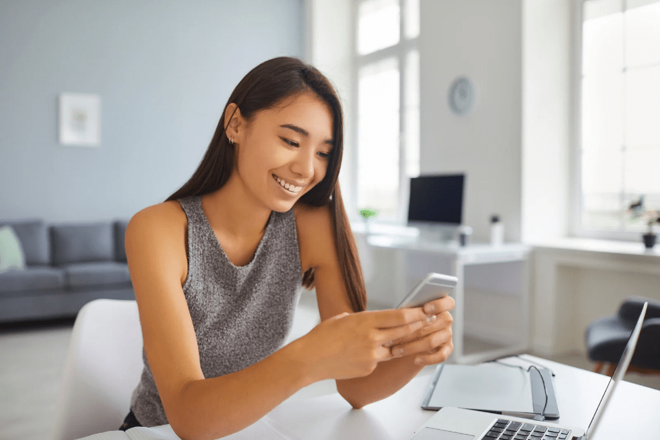 Smiling Filipino Woman Scrolling Through Social Media on Her Mobile Phone