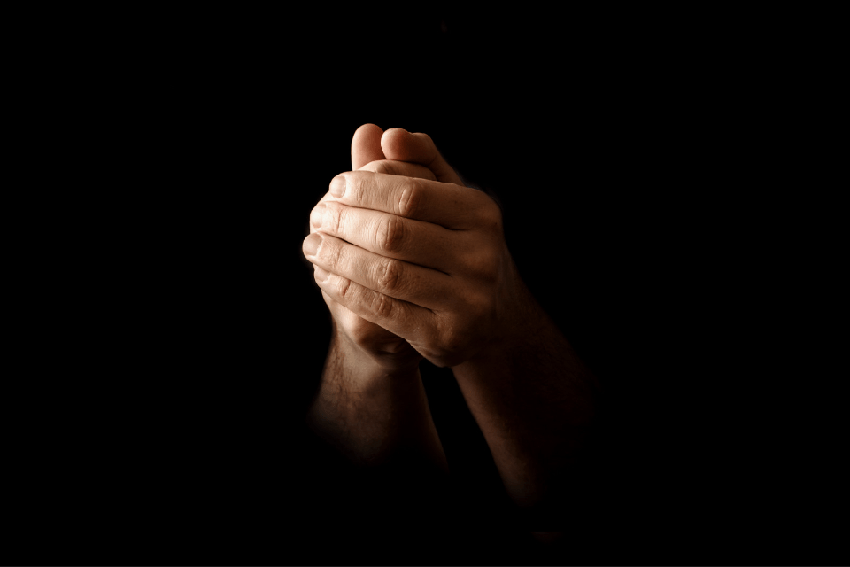 Man's Hands in Faithful Prayer and Respect on a Black Background