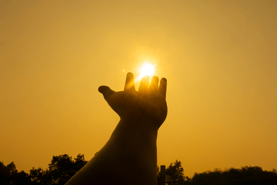 Hand catching the sun during sunset, concept of spiritual compatibility in Christian Filipina dating.