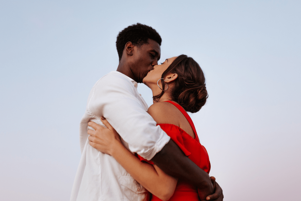Interracial couple sharing an intimate kiss after successfully navigating financial requests in online relationships.