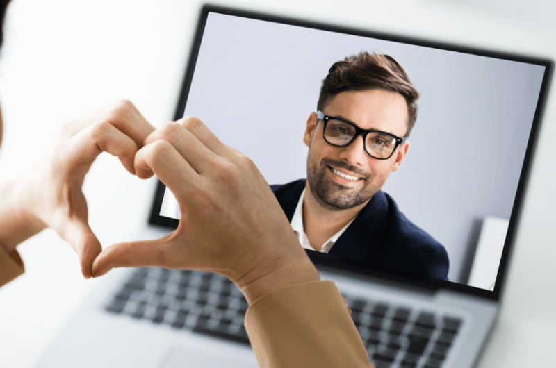 Online video call on laptop computer with the woman making a small gesture (heart)