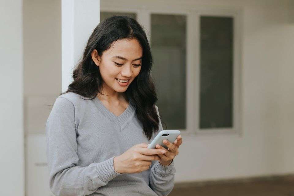 Stunning Smiling Filipino Woman Texting - Signs a Filipina Likes You - Blossoms Dating Blog